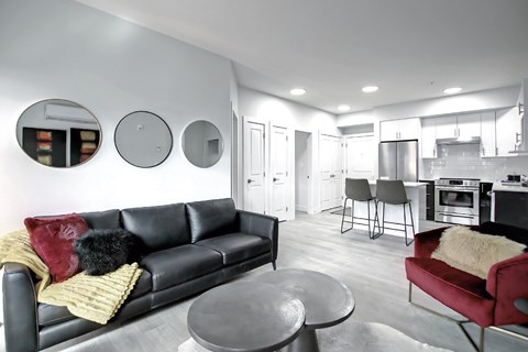 A black leather couch with a yellow throw blanket sits in a modern living room.
