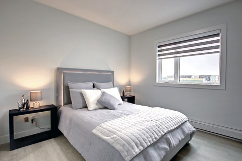 A bedroom with a large bed and a window with blinds.