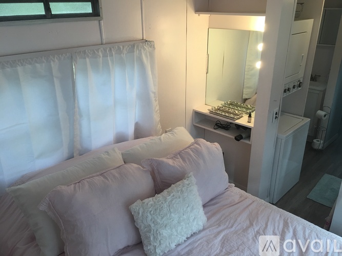 A bedroom with a bed, a mirror, and a window with curtains.