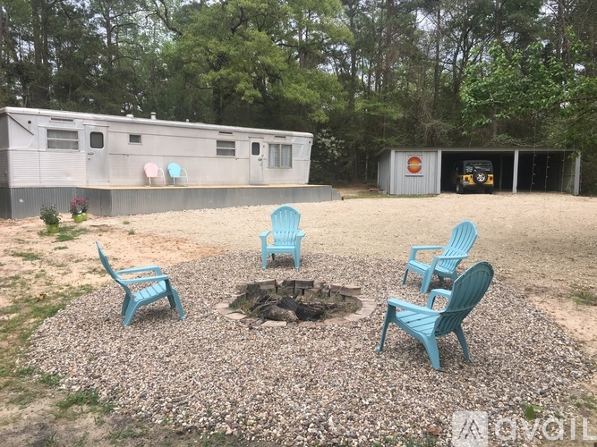 A fire pit surrounded by four chairs in a gravel area.