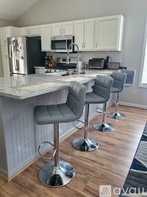 A kitchen with a bar area featuring a white counter and grey bar stools.