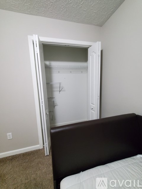 A bedroom with a bed and a wardrobe with an open door.