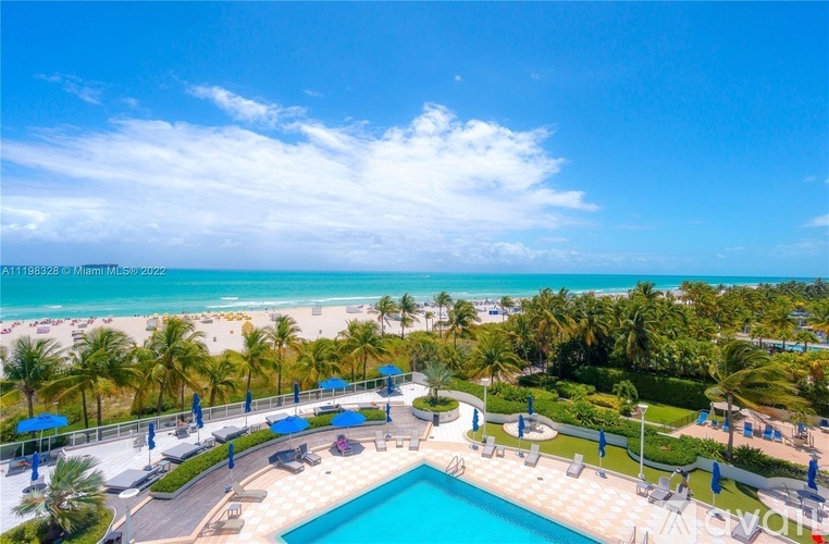 A beautiful beachfront resort with a swimming pool and palm trees.