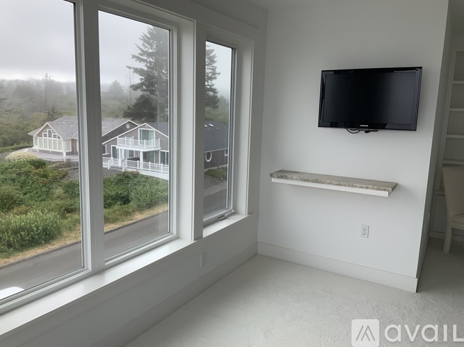 A room with a large window overlooking a house and trees.