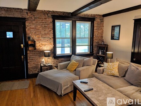 A living room with a grey couch and a brick wall.