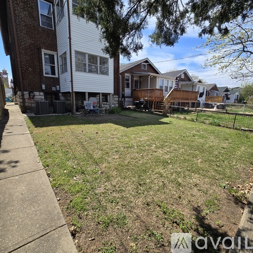 A grassy area in front of a house with a tree and a fence.