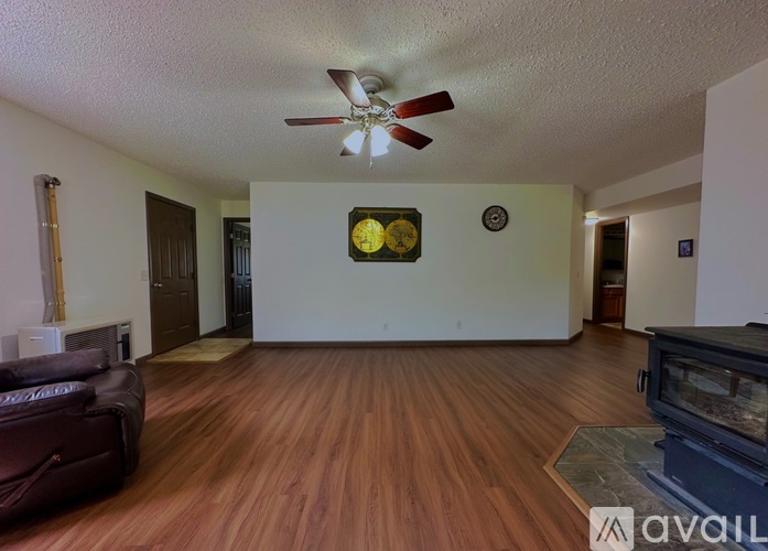 A living room with a brown leather couch and a wooden floor.