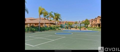 A tennis court surrounded by palm trees and residential buildings.