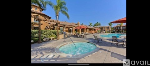 A pool surrounded by chairs and a building in the background.