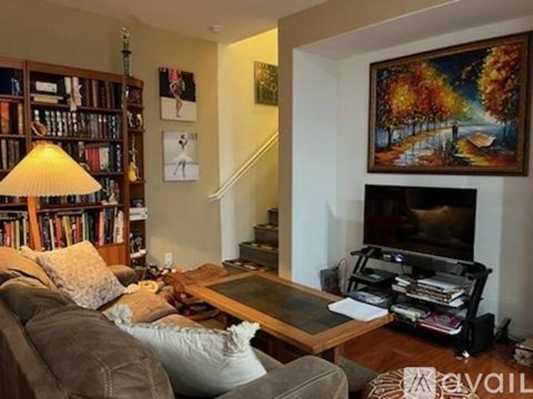A living room with a grey couch, a coffee table, a bookshelf, a painting, and a fireplace.