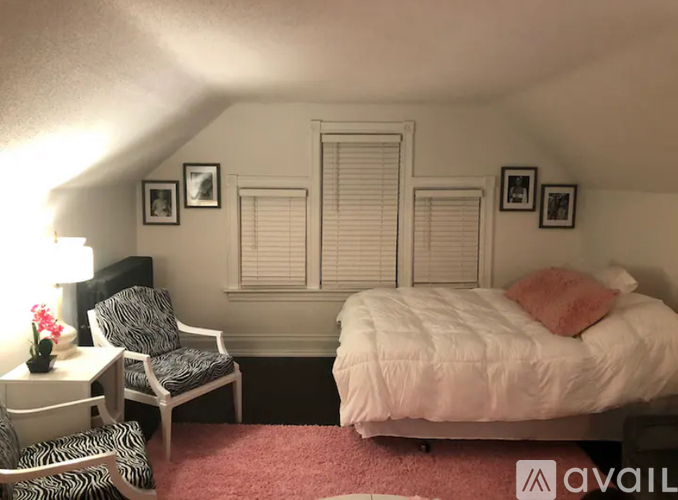 A bedroom with a bed, chair, and pictures on the wall.