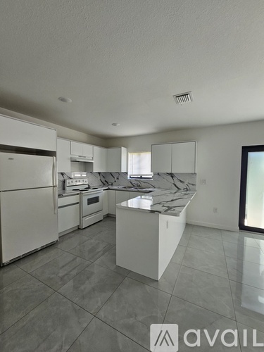 A kitchen with white appliances and a marble countertop.