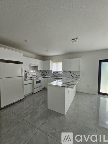 A kitchen with white appliances and a marble countertop.