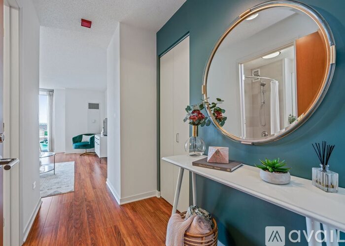 A hallway with a round mirror and a white console table with a plant on it.
