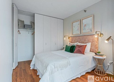 A bedroom with a white bed and a wooden floor.