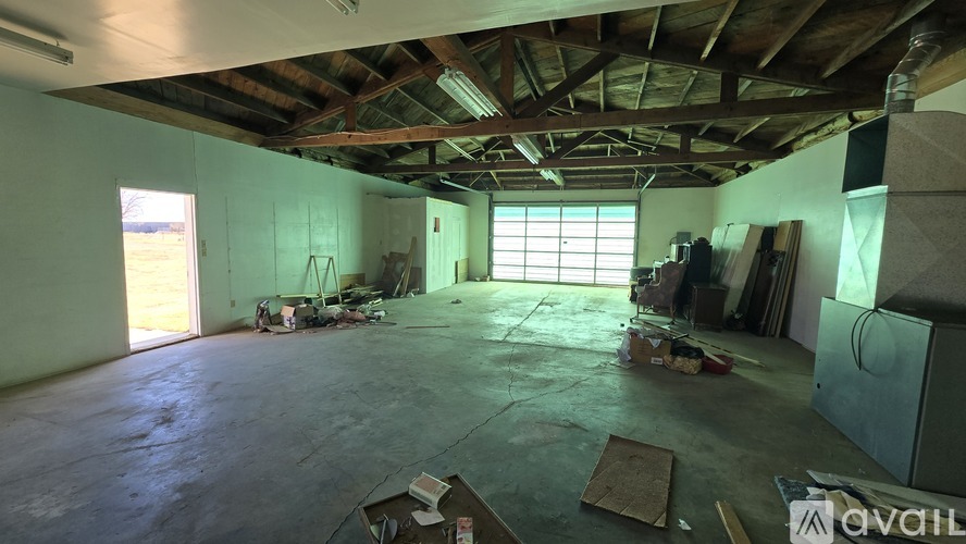 A large empty room with wooden beams on the ceiling and a window on the wall.