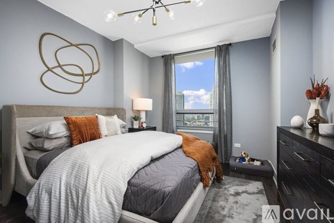 A bedroom with a large bed, a window with a view of the city, and a chandelier.