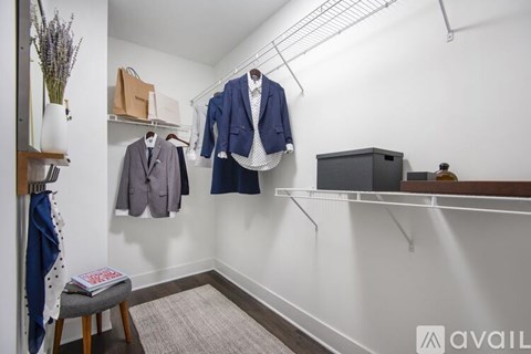 A room with a white wall and a shelf with clothes hanging on it.