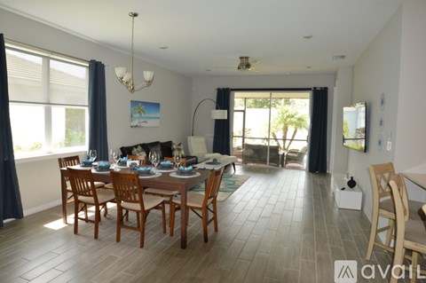 A dining room with a table set for six with a view of the backyard.
