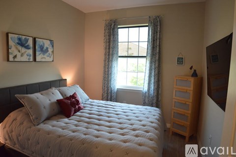 A bedroom with a large bed and a window with curtains.