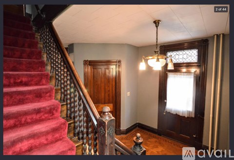 A staircase with a red carpet and a wooden banister.