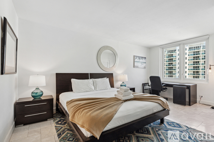 A bedroom with a large bed and a window with blinds.