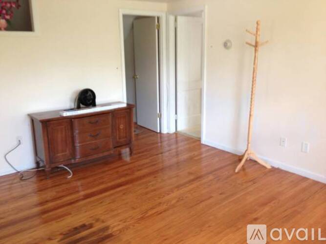 A room with a wooden floor and a wooden cabinet with a speaker on top.