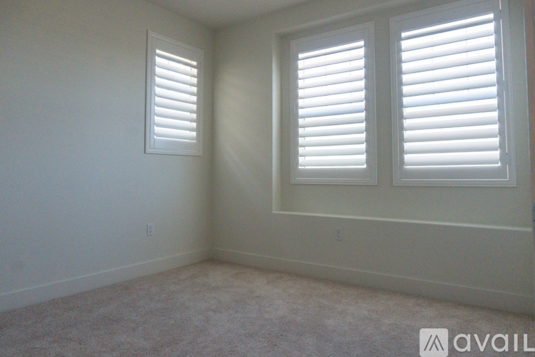 A room with two windows covered by white blinds.