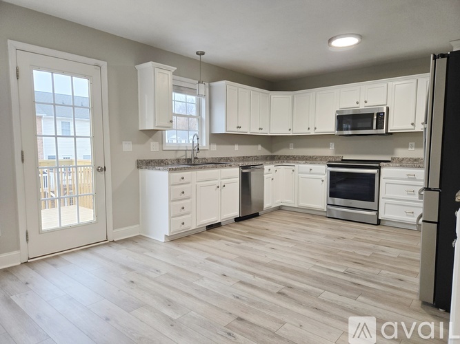 A kitchen with white cabinets and a wooden floor.