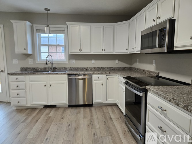 A kitchen with white cabinets and a granite countertop.