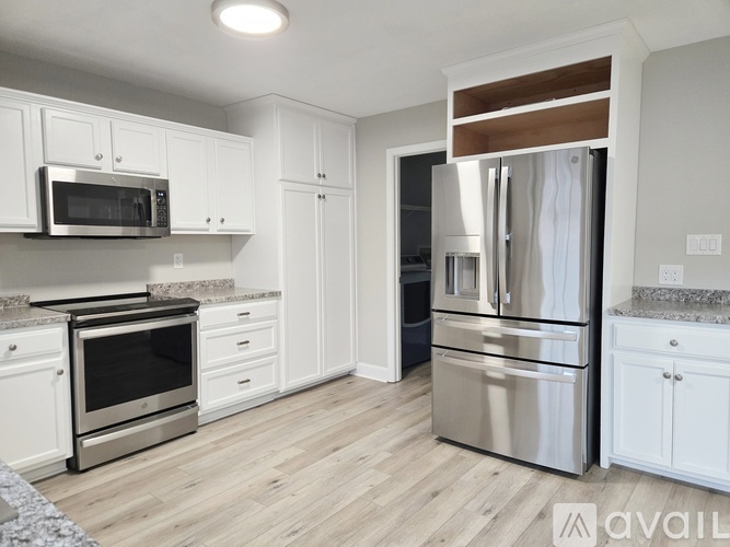 A kitchen with white cabinets and a stainless steel refrigerator.
