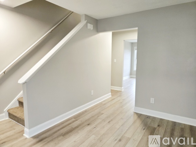 A spacious room with wooden flooring and a staircase leading to another level.
