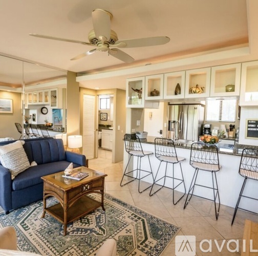 A living room with a blue couch and a bar area with stools.