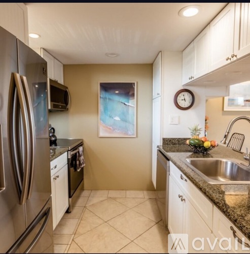A kitchen with a refrigerator, microwave, and a clock on the wall.