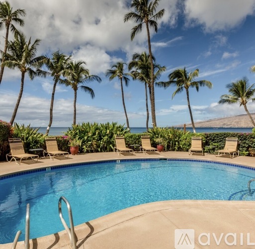 A pool surrounded by palm trees and beach chairs.