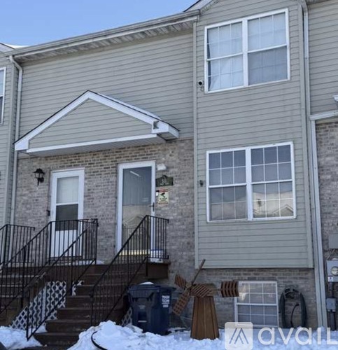 A house with a grey siding and a black railing on the stairs.