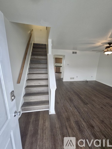 A room with wooden floors and a staircase leading to another room.