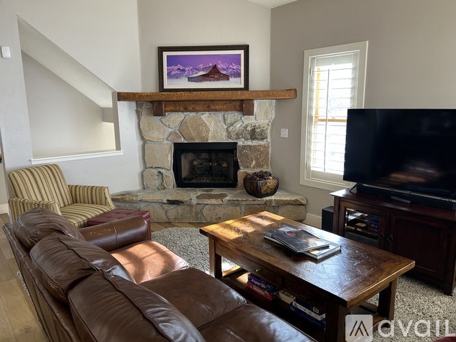 A living room with a brown leather couch and a stone fireplace.