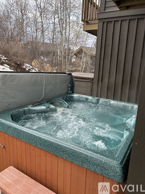 A hot tub on a wooden deck with a grey cover.