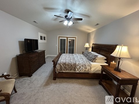 A bedroom with a bed, dresser, and ceiling fan.