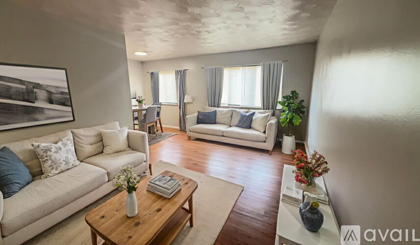 A living room with a white couch, a coffee table, and a painting on the wall.