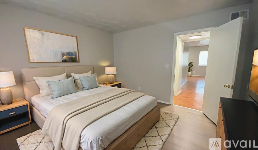 A bedroom with a large bed and a painting on the wall.