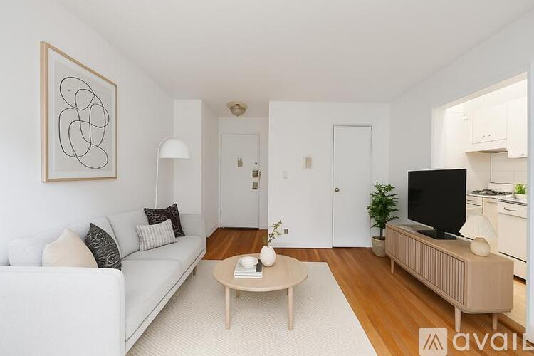 A living room with a white couch, a coffee table, and a television.
