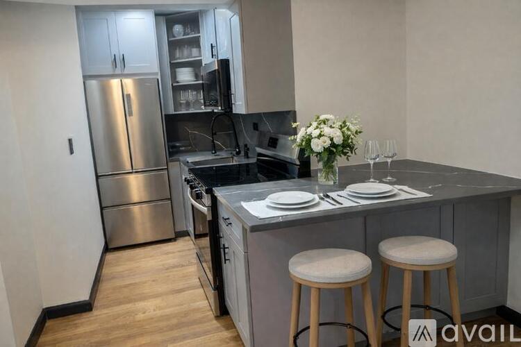 A kitchen with a refrigerator, stove, and bar stools.