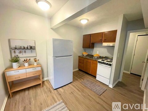 A kitchen with a white refrigerator, wooden cabinets, and a wooden table with drawers.