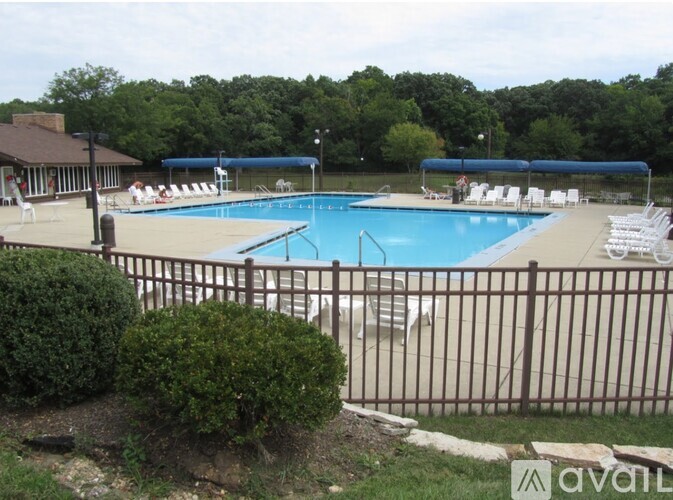 A pool surrounded by a fence with chairs and a building in the background.