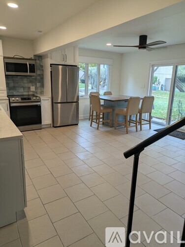 A kitchen with a refrigerator, oven, and a dining table with chairs.