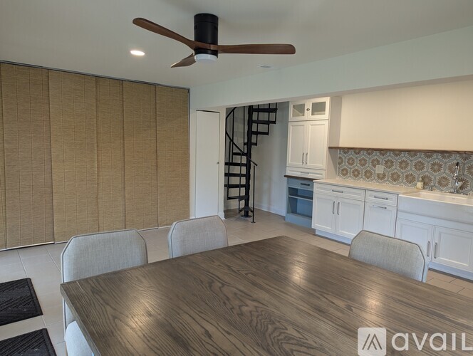A dining room with a wooden table and chairs and a ceiling fan.