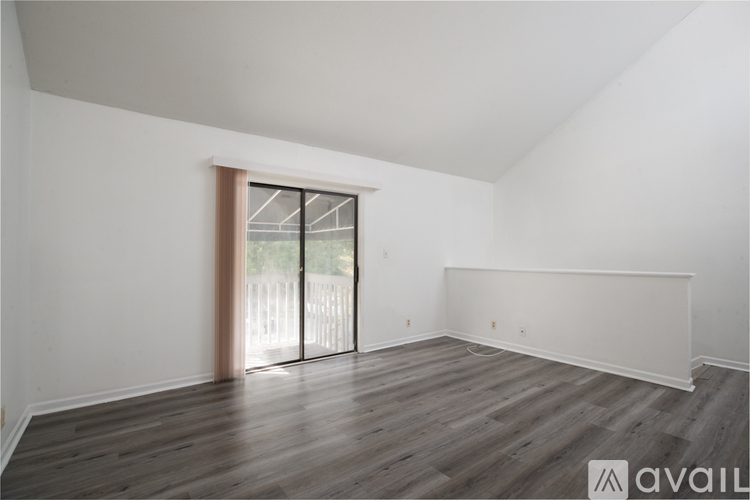 A room with wooden flooring and a sliding glass door.