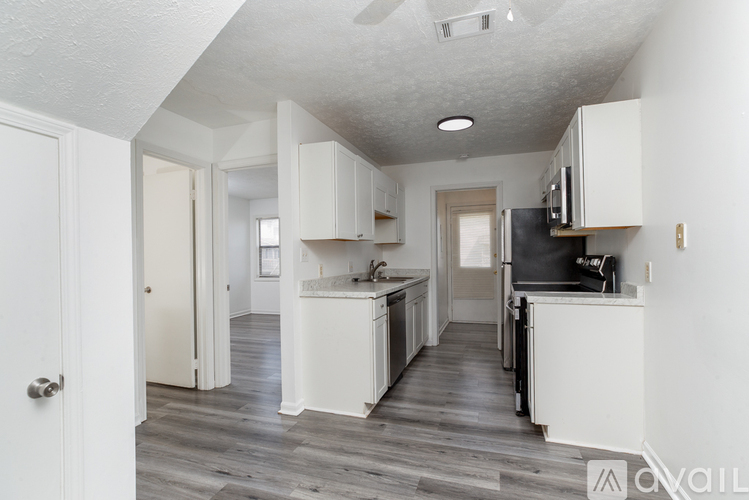A kitchen with white cabinets and a black fridge.